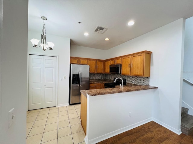 kitchen featuring light wood-type flooring, tasteful backsplash, hanging light fixtures, kitchen peninsula, and stainless steel appliances