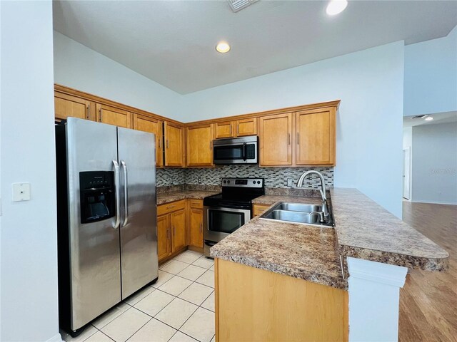 kitchen with sink, light wood-type flooring, decorative backsplash, stainless steel appliances, and kitchen peninsula