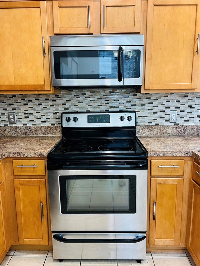 kitchen with decorative backsplash, appliances with stainless steel finishes, and light tile patterned floors