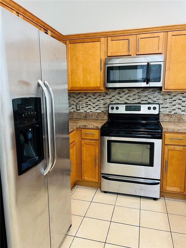 kitchen with appliances with stainless steel finishes, light tile patterned flooring, and tasteful backsplash