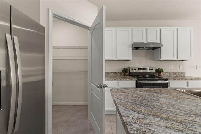 kitchen featuring white cabinets, stainless steel appliances, dark stone counters, and light tile patterned flooring