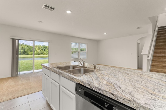 kitchen featuring light stone counters, sink, white cabinets, dishwasher, and light colored carpet