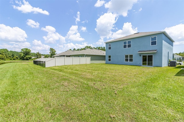 back of house with central AC unit and a yard