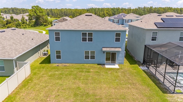 rear view of house featuring a swimming pool, glass enclosure, and a yard