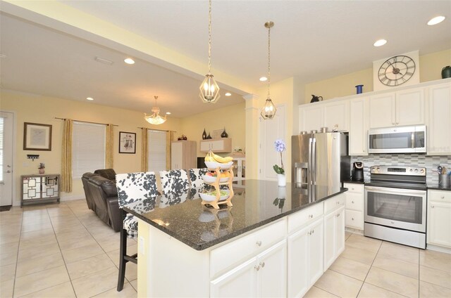 kitchen featuring a center island, hanging light fixtures, appliances with stainless steel finishes, white cabinets, and backsplash