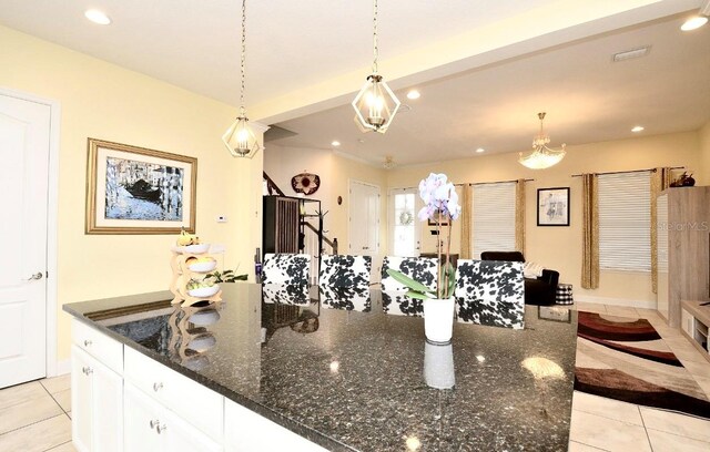 kitchen featuring white cabinetry, pendant lighting, dark stone countertops, and light tile patterned flooring