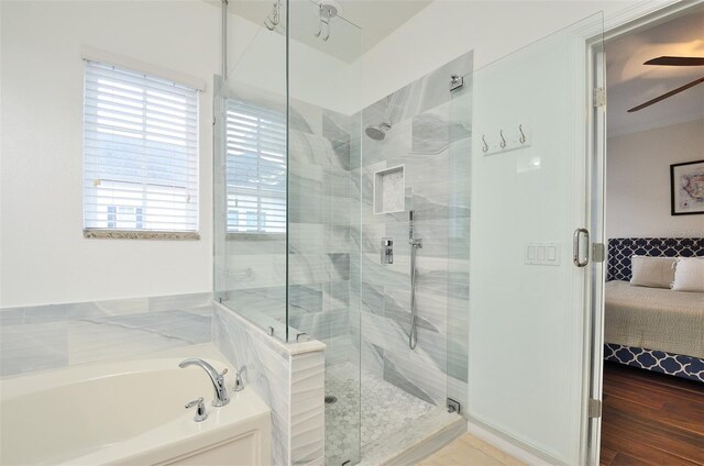 bathroom with ceiling fan, shower with separate bathtub, and hardwood / wood-style floors