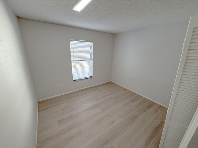 spare room with a textured ceiling and light hardwood / wood-style floors