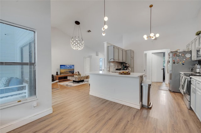 kitchen with decorative light fixtures, stainless steel appliances, an inviting chandelier, and light hardwood / wood-style flooring