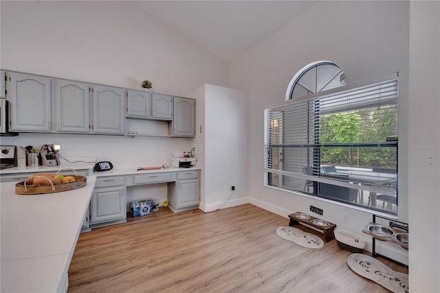 kitchen with high vaulted ceiling, light wood-type flooring, and gray cabinetry