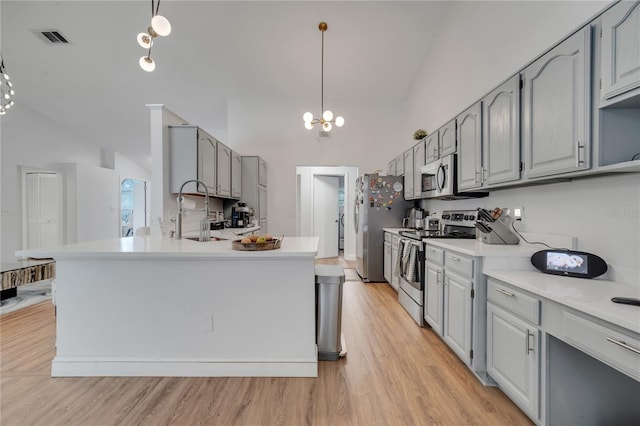 kitchen with light wood-type flooring, sink, gray cabinets, appliances with stainless steel finishes, and pendant lighting