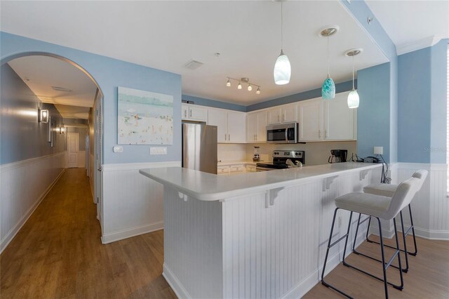 kitchen featuring rail lighting, kitchen peninsula, light hardwood / wood-style floors, and stainless steel appliances