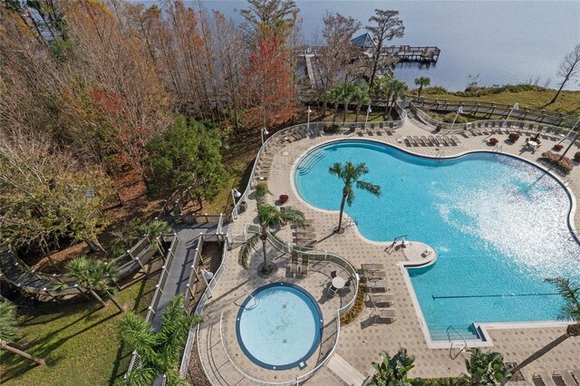 view of swimming pool featuring a patio, a jacuzzi, and a water view