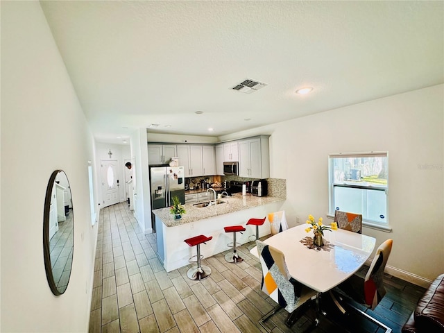 kitchen featuring appliances with stainless steel finishes, decorative backsplash, light hardwood / wood-style floors, and kitchen peninsula