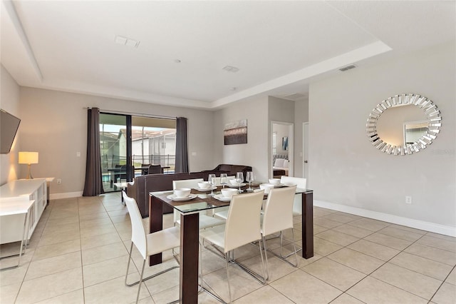 dining room featuring a tray ceiling and light tile patterned floors