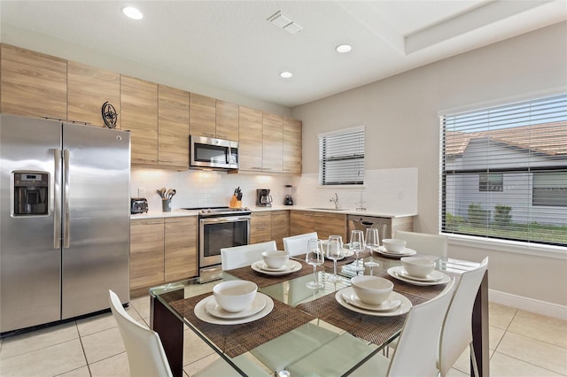 kitchen featuring appliances with stainless steel finishes, light tile patterned floors, and a healthy amount of sunlight