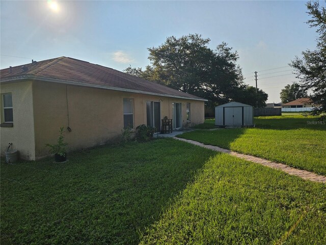 rear view of property featuring a storage unit, central AC unit, and a yard