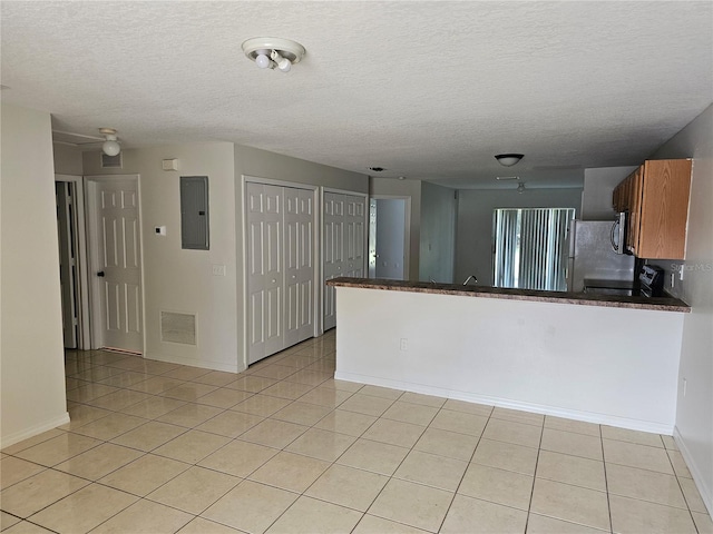 kitchen featuring light tile patterned flooring, kitchen peninsula, range, and electric panel