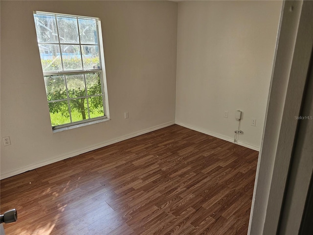 empty room featuring dark wood-type flooring and baseboards