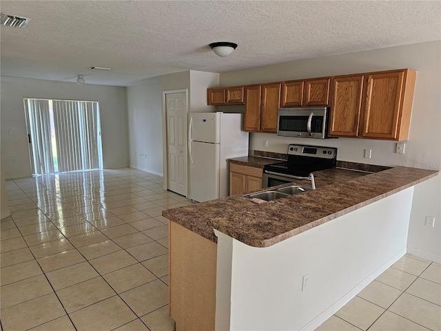 kitchen with appliances with stainless steel finishes, a textured ceiling, light tile patterned floors, and kitchen peninsula