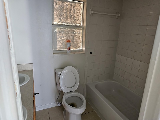 bathroom with baseboards, toilet, tile patterned floors, shower / bathtub combination, and a sink