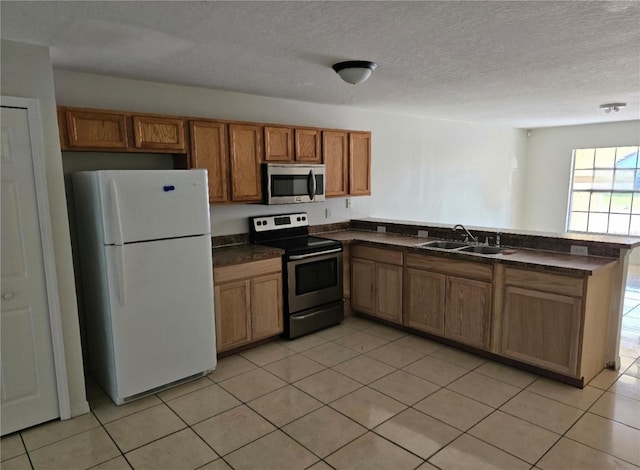 kitchen with sink, a textured ceiling, light tile patterned floors, stainless steel appliances, and kitchen peninsula