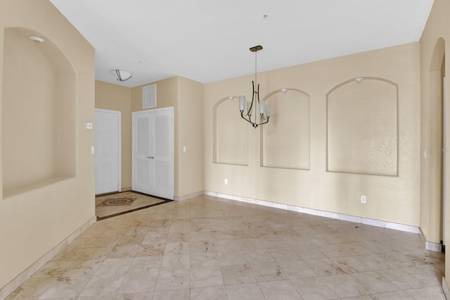 unfurnished room featuring a chandelier