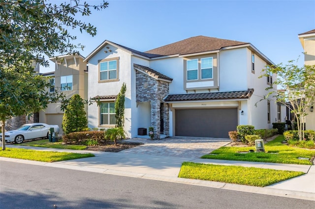 view of front of property with decorative driveway, stone siding, an attached garage, and stucco siding