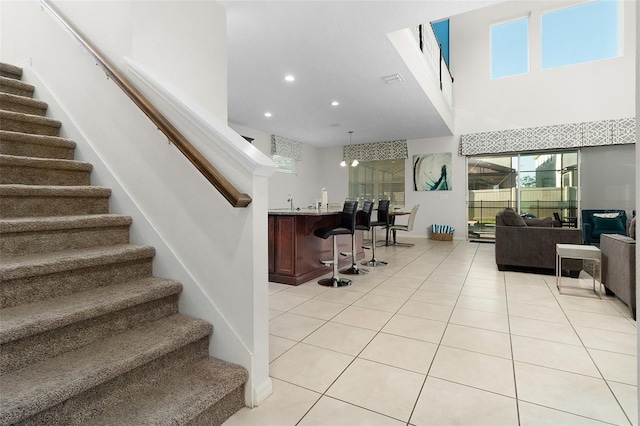 interior space with stairway, light tile patterned floors, a high ceiling, recessed lighting, and pendant lighting