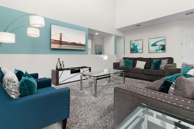 living area featuring a high ceiling and visible vents