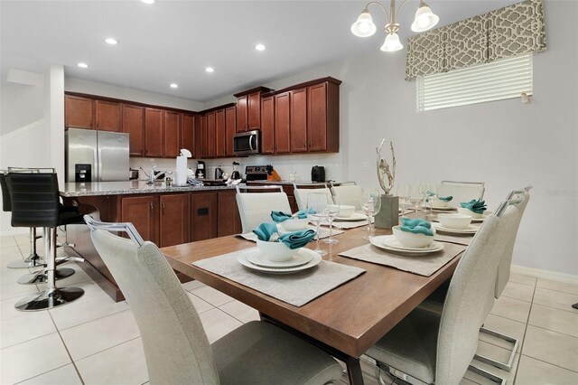 kitchen with light tile patterned floors, a chandelier, stainless steel appliances, and hanging light fixtures