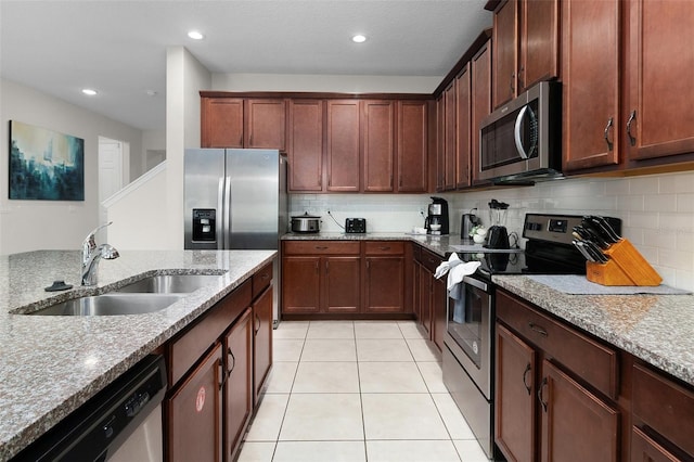 kitchen with sink, appliances with stainless steel finishes, decorative backsplash, light stone countertops, and light tile patterned floors