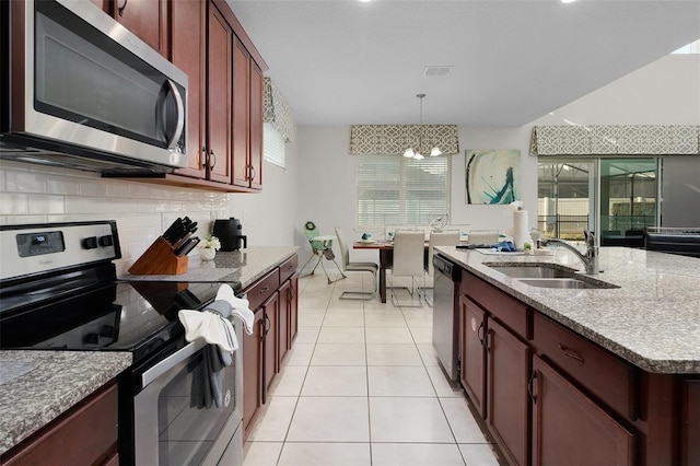 kitchen featuring backsplash, pendant lighting, a chandelier, appliances with stainless steel finishes, and sink