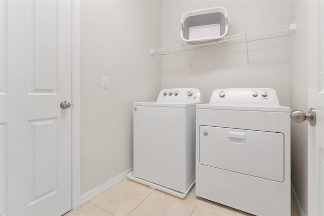 laundry area featuring laundry area, light tile patterned floors, washing machine and dryer, and baseboards