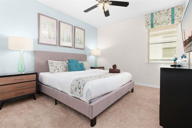 bedroom with light colored carpet, baseboards, and ceiling fan