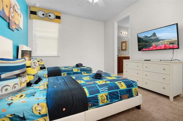 bedroom featuring ceiling fan, light colored carpet, and ensuite bath