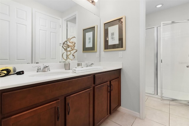 full bath with a shower stall, baseboards, double vanity, tile patterned floors, and a sink