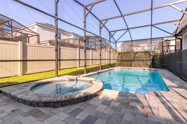 view of pool with glass enclosure, an in ground hot tub, and a patio