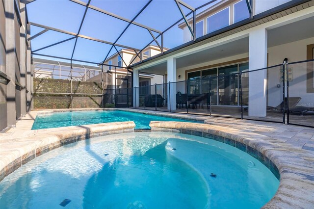 view of swimming pool featuring an in ground hot tub, glass enclosure, and a patio