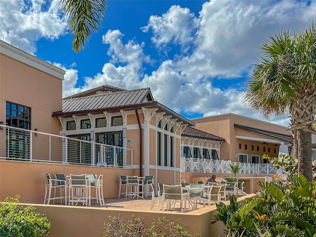 back of property with stucco siding, metal roof, and a standing seam roof