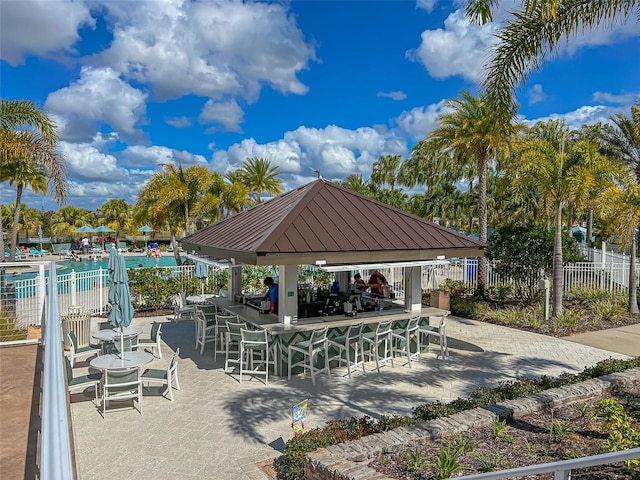 view of property's community featuring a gazebo, outdoor dry bar, a patio, and fence