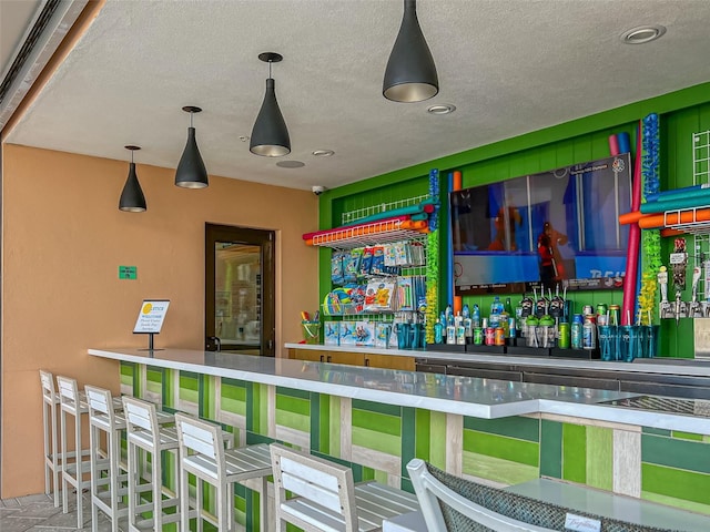 bar featuring hanging light fixtures, a textured ceiling, and a bar