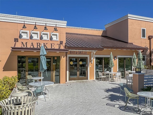 exterior space featuring a patio, a standing seam roof, stucco siding, french doors, and metal roof