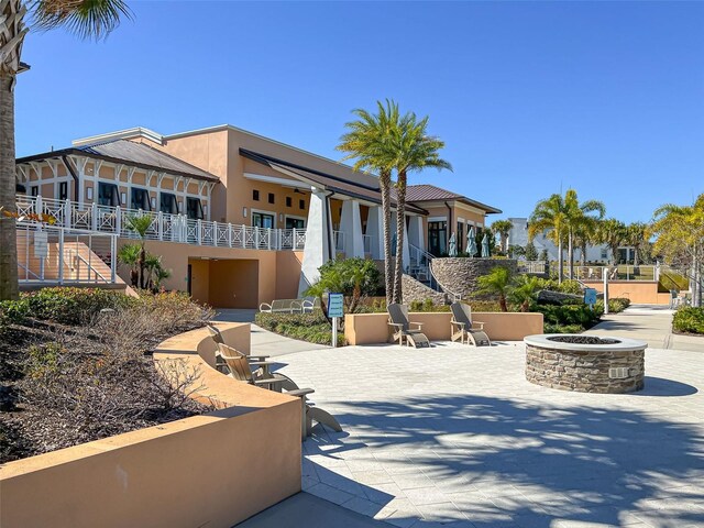 view of front facade featuring stucco siding, a fire pit, stairs, and a patio area