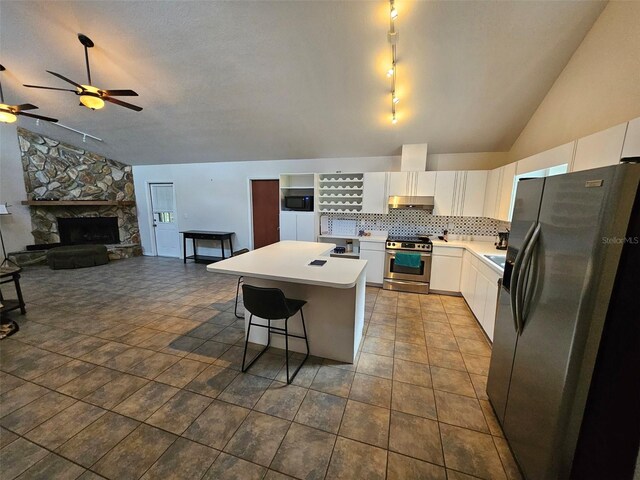 kitchen with vaulted ceiling, appliances with stainless steel finishes, white cabinetry, a kitchen island, and a kitchen breakfast bar