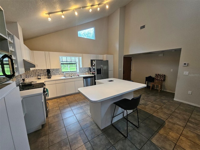 kitchen featuring white cabinetry, backsplash, high vaulted ceiling, and appliances with stainless steel finishes