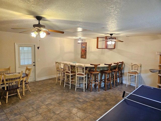 dining room with dark tile patterned flooring, ceiling fan, and a textured ceiling