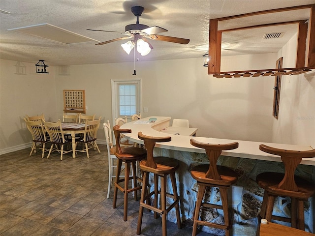 tiled dining space featuring a textured ceiling and ceiling fan