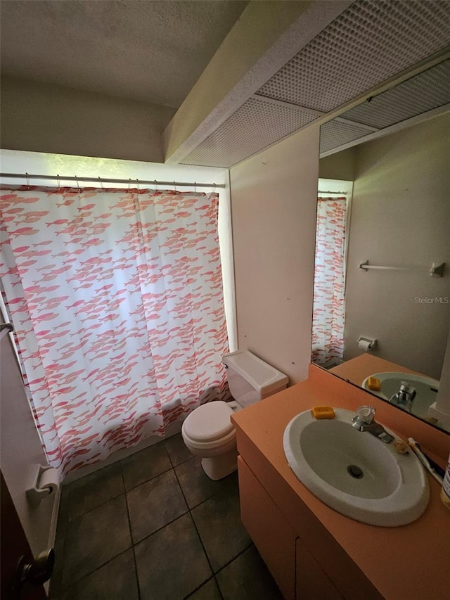 bathroom with toilet, vanity, and tile patterned floors