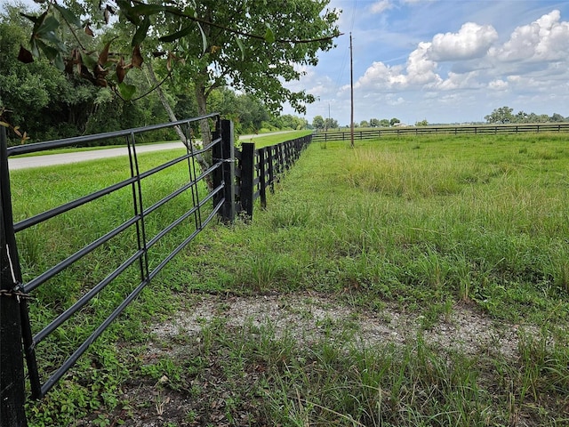 view of gate with a rural view and a yard